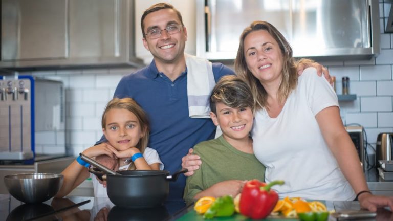 A joyful family of four cooking together in a modern kitchen, highlighting family bonding and culinary activities.